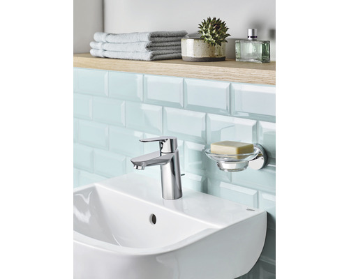 Badezimmer Waschbecken mit Armatur, Seifenschale, Handtüchern und Accessoires auf einem Regal