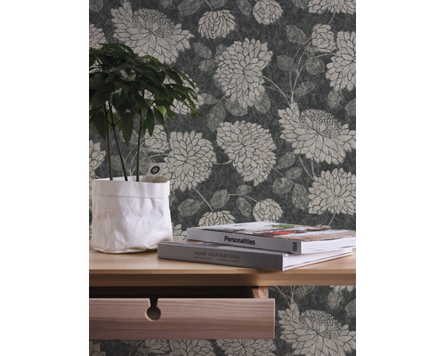 Innenraumszene mit floral gemusterter Tapete, Holztisch mit Pflanze und Büchern