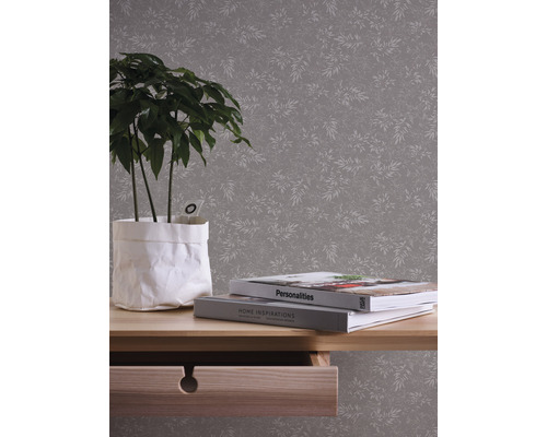 Szene mit einer gemusterten Tapete, einem Tisch mit einer Pflanze und Büchern