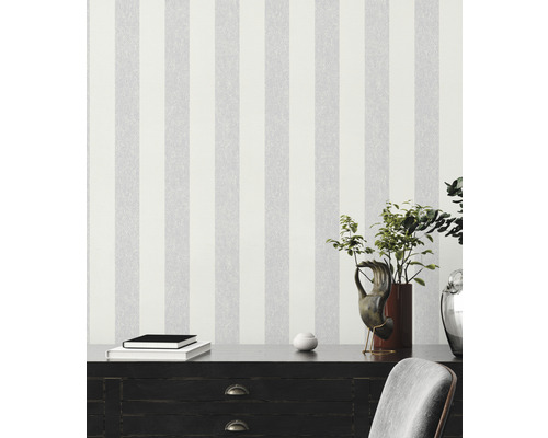 Szene mit gestreifter Tapete, Kommode, Büchern und Dekorationen für eine moderne Raumgestaltung.