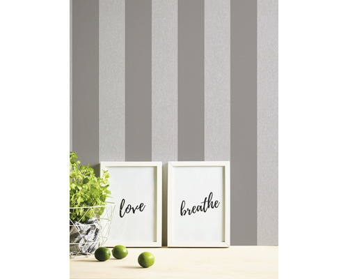Grau gestreifte Tapete mit zwei gerahmten Kunstdrucken und einer Pflanze auf einem Tisch