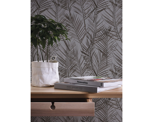 Nahaufnahme eines Zimmers mit einer botanischen Tapete, einem Holztisch, Büchern und einer Zimmerpflanze