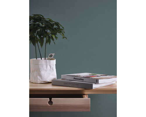 Dekoratives Stillleben mit Pflanze in Papiertüte, Büchern und Schubladentisch