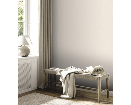 Heller Raum mit Bank, Buch, Tuch und Dekor neben Fenster mit Vorhang