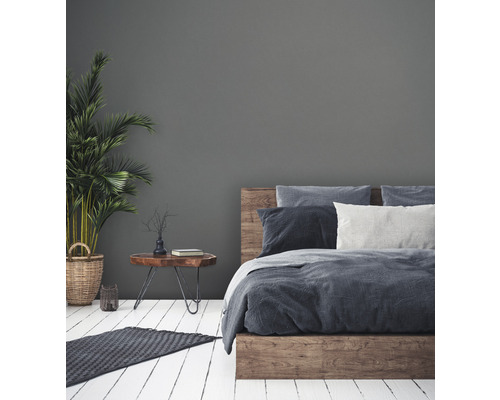 Schlafzimmer mit Holzbett, Nachttisch und Zimmerpflanze