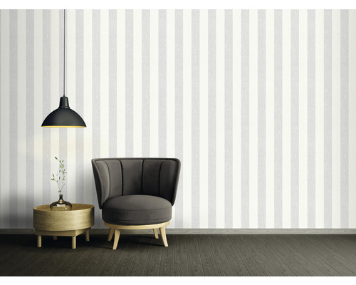 Dekoratives Zimmer mit Streifentapete, Sessel, Lampe und Beistelltisch