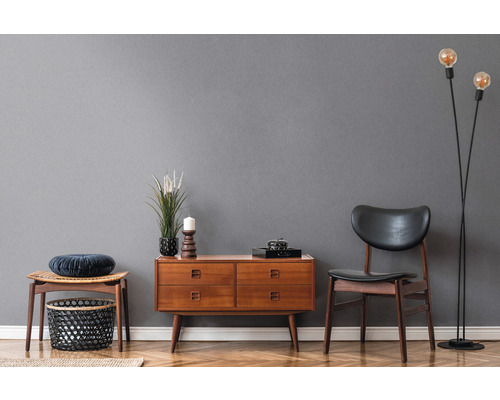 Wohnzimmer mit Holzkommode, Stuhl, Hocker und Stehlampe