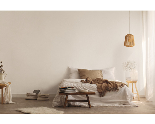 Helles Schlafzimmer mit Bett, Decke, Kissen, Lampe, Tisch und Dekorationen für eine gemütliche Atmosphäre