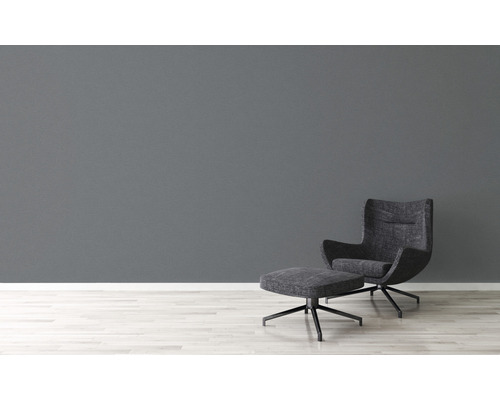 Modernes Wohnzimmer mit Sessel und Fußhocker auf hellem Holzboden