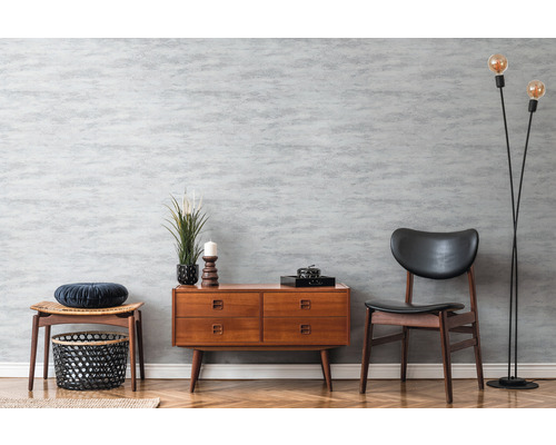 Wohnraum mit Kommode, Stuhl und Stehlampe im Retro-Stil vor grauer Wand