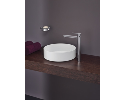 Badezimmer Waschbecken mit Armatur, Seifenschale und Handtüchern auf einer Holzablage.