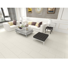Elegantes Wohnzimmer mit weißen Sofas, Couchtisch und Fußhocker auf beigem Fliesenboden.