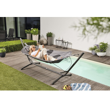 Frau liest in einer grauen Hängematte mit Gestell auf einer Terrasse