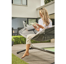 Frau liest Buch in Hängematte im Garten