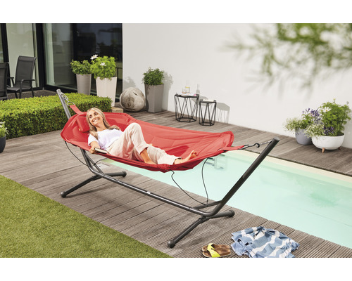 Frau entspannt in Hängematte mit Gestell im Garten.