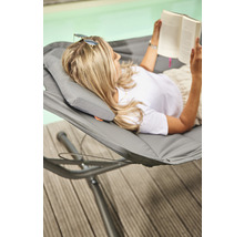 Frau liest Buch in Hängematte am Pool