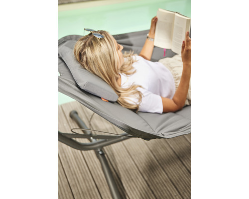 Frau liest Buch in Hängematte am Pool