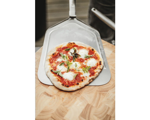 Pizza auf Pizzaschieber und Holzbrett
