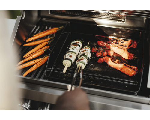 Gemüse wie Karotten, Zucchini-Spieße und Paprika auf einem Grill.