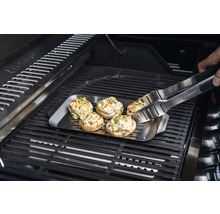 Gefüllte Champignons auf einer Grillplatte mit Grillzange auf einem Grill.