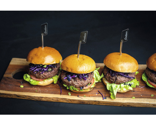 Mehrere Burger mit Fleisch, Salat und Enders Fähnchen auf einem Holzbrett