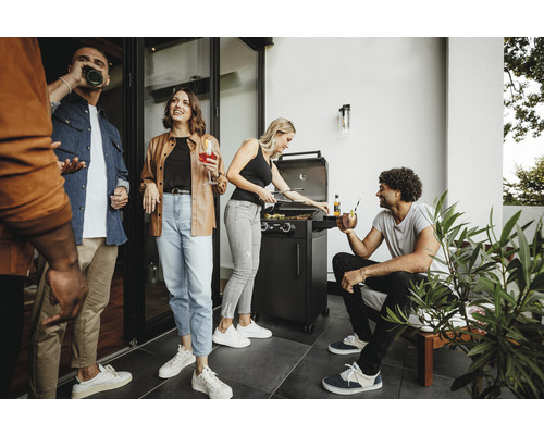 Personen grillen mit einem Gasgrill auf einer Terrasse.