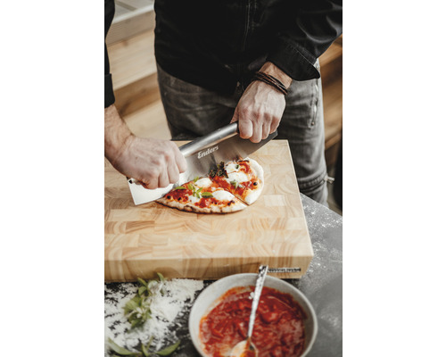 Eine Person schneidet Pizza auf einem Holzbrett mit einem Pizzaschneider der Marke Enders.