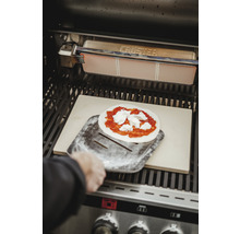 Pizza auf einem Pizzaschieber im Grill mit Pizzastein