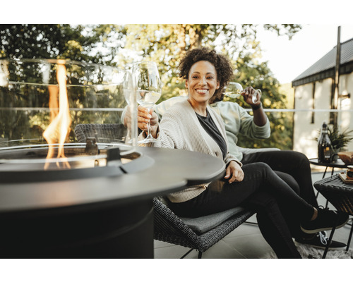 Paar entspannt auf der Terrasse mit Feuerstelle und Getränken