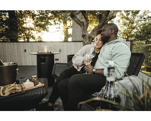 Paar genießt Wein auf der Terrasse mit Gasheiztisch und Snacks