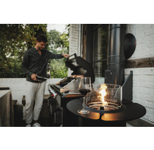 Szene mit einem Mann, der im Garten grillt, einem Glas Rotwein und einer Feuerstelle