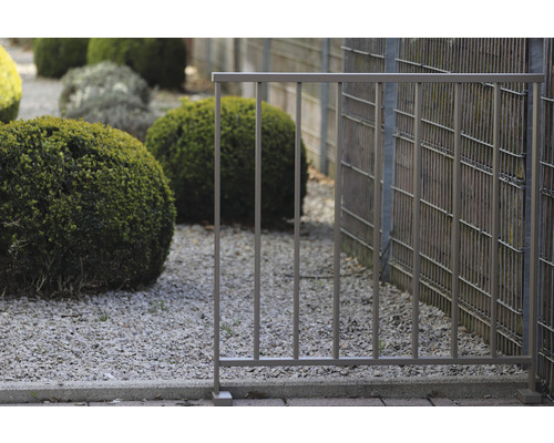 Metallzaun im Gartenbereich mit Kies und Büschen