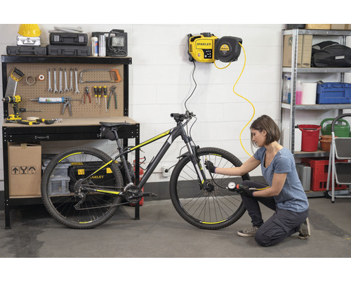 Frau pumpt Fahrradreifen mit Druckluftkompressor in Werkstatt.