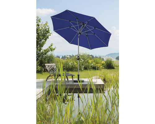 Blauer Sonnenschirm neben einem Teich und einer Holzterrasse im Garten.