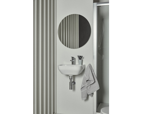 Badezimmer Waschbecken mit rundem Spiegel, Armatur, Handtuch und Accessoires