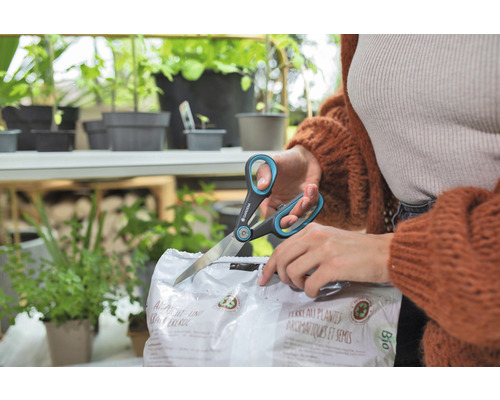 Eine Person öffnet eine Packung Anzucht- und Kräutererde mit einer Schere der Marke Gardena.