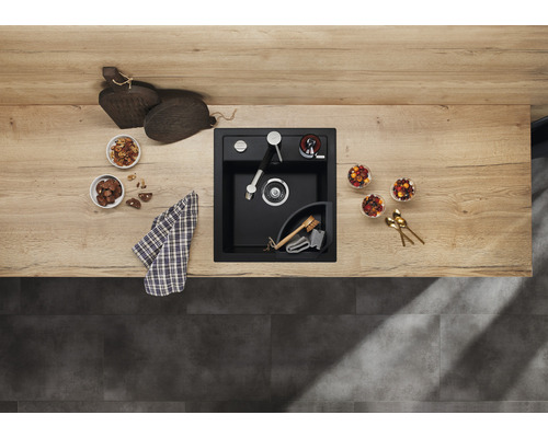 Schwarze Küchenspüle mit Armatur, Spülmittelspender und Eckablage auf einer Arbeitsplatte