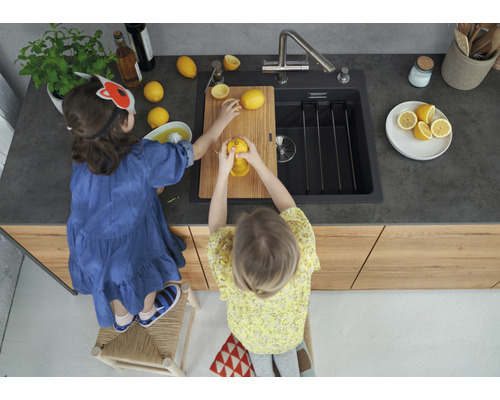 Zwei Kinder stehen an einer Küchenspüle und pressen Zitronen aus.