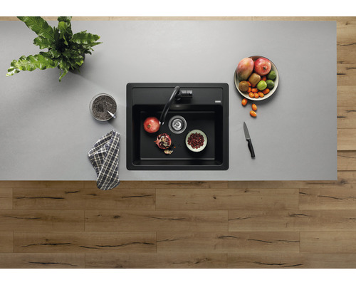 Draufsicht auf eine Spüle mit Armatur, umgeben von Obst und Küchenutensilien.