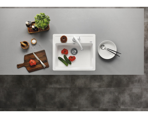 Küchenspüle mit Armatur, Schneidebrett, Geschirr und Lebensmitteln auf einer Arbeitsplatte