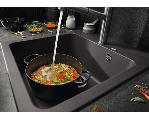 Spüle mit Wasserhahn und einem Topf gefüllt mit Gemüse