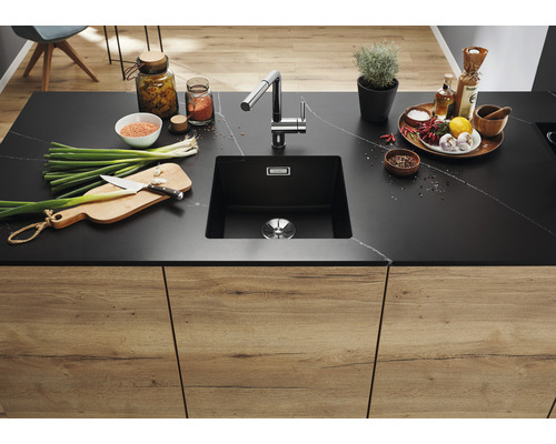 Küchenspüle mit Armatur und Lebensmitteln auf einer Arbeitsplatte