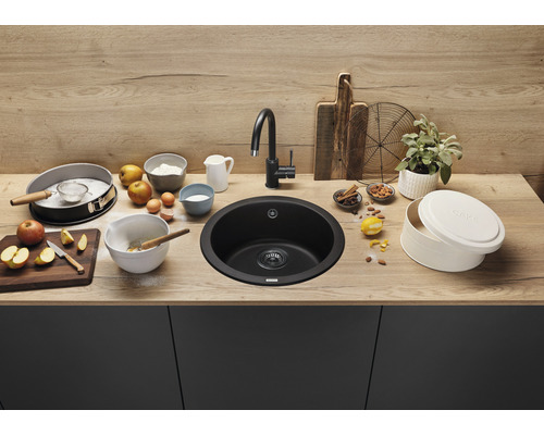 Runde, schwarze Küchenspüle mit Armatur und Backzutaten auf einer Küchentheke