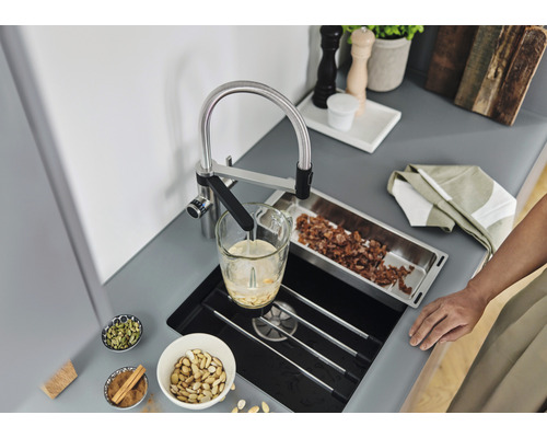 Küchenszene mit Spültischarmatur, Spüle, Lebensmitteln und Küchenutensilien auf einer Arbeitsplatte.