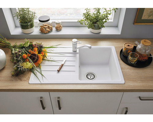 Küchenspüle mit Armatur, Blumenstrauß und Küchenutensilien auf einer Küchentheke