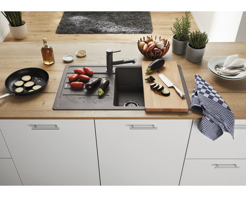 Küchenszene mit Spüle, Armatur, Schneidebrett und Gemüse auf einer Arbeitsplatte