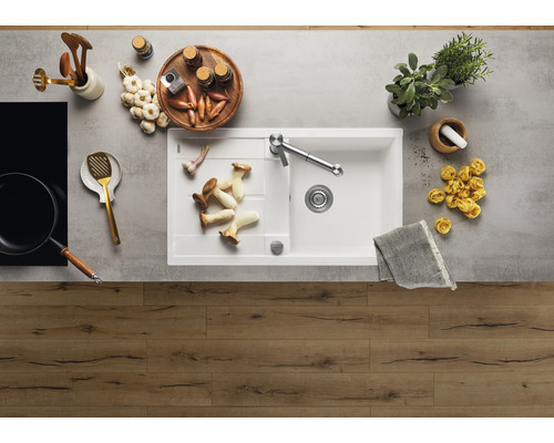 Küchenspüle mit Armatur, umgeben von Lebensmitteln und Küchenutensilien auf einer Arbeitsfläche