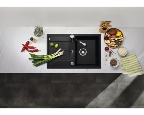 Spüle aus Verbundwerkstoff mit Abtropffläche und Küchenarmatur, umgeben von Lebensmitteln auf einer Küchentheke.