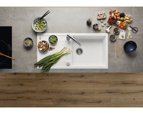 Küchenspüle mit Armatur und Zutaten für die Zubereitung von Speisen auf einer Arbeitsplatte.