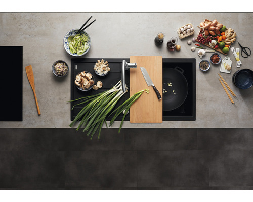 Küchenspüle mit Armatur, Schneidebrett, Messer, Wokpfanne und verschiedenen Zutaten für die Zubereitung asiatischer Gerichte.